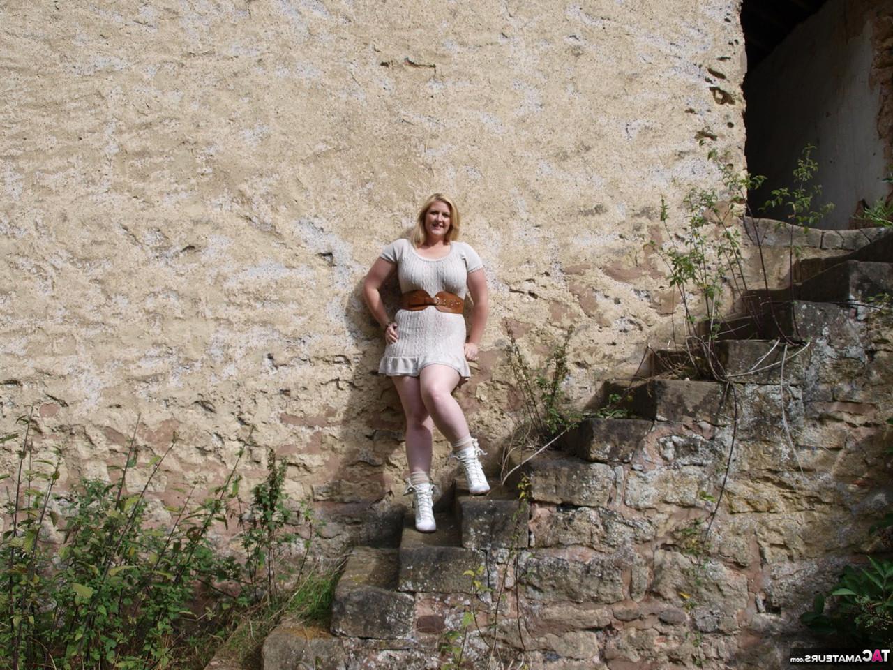 16P Samantha, blonde en surpoids, se déshabille devant la porte d'un immeuble abandonné.
