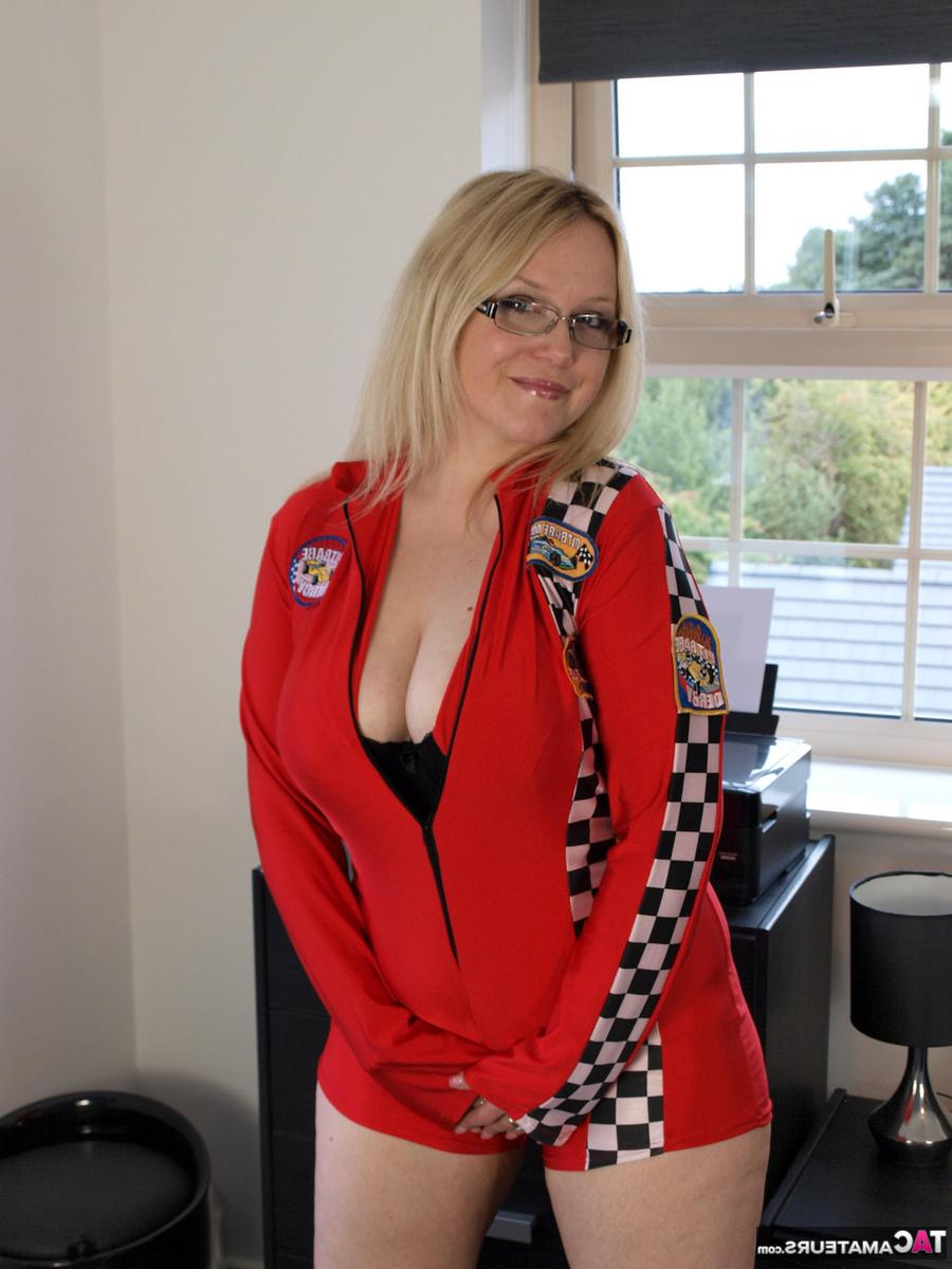 16P La blonde britannique Sindy Bust se met nue sur un lit avec des lunettes et des talons.