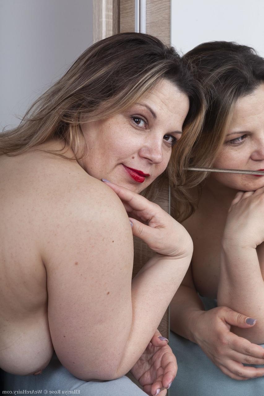 20P La brune potelée Ellariya Rose se déshabille et écarte sa chatte poilue.