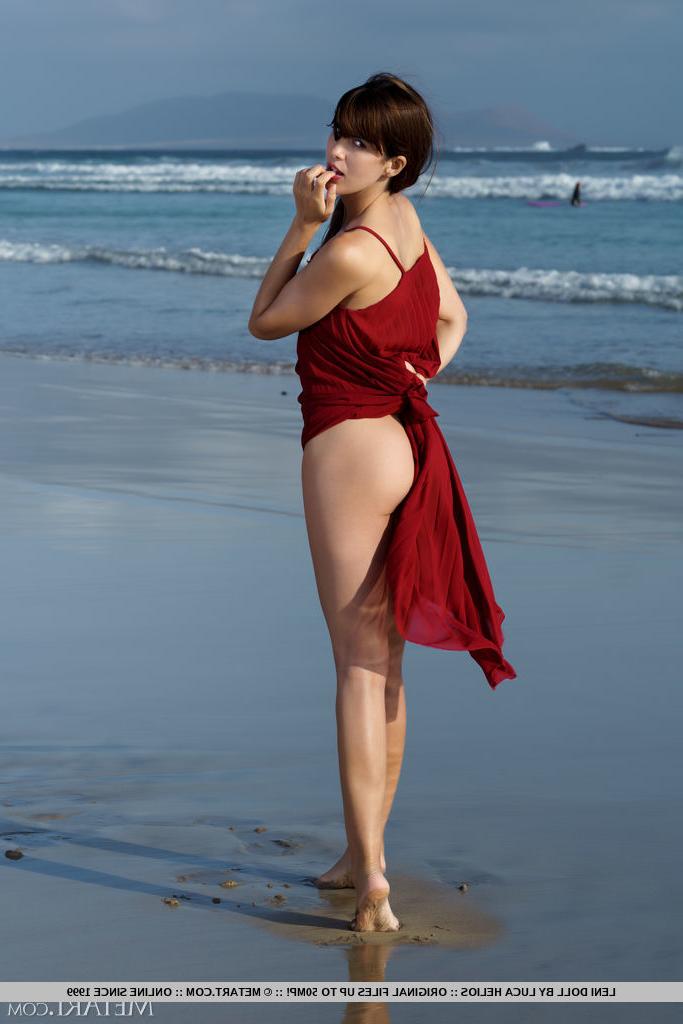 18P La jolie jeune Leni Doll se met complètement nue à la plage.