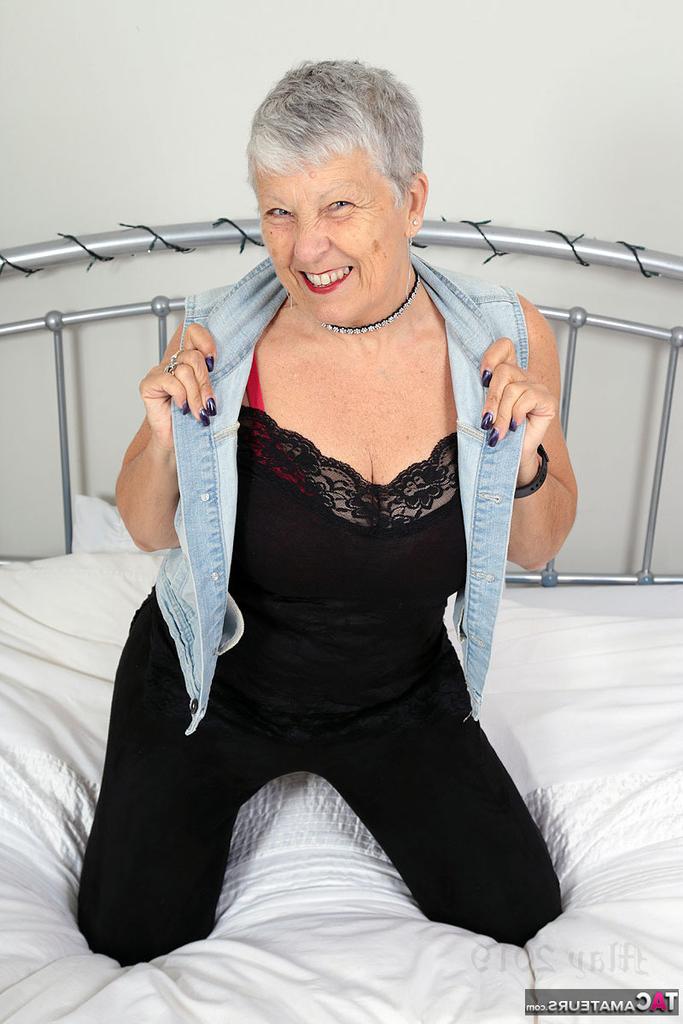 20P Savana, une vieille amatrice, lâche ses gros seins sur un lit dans un gilet en jean.
