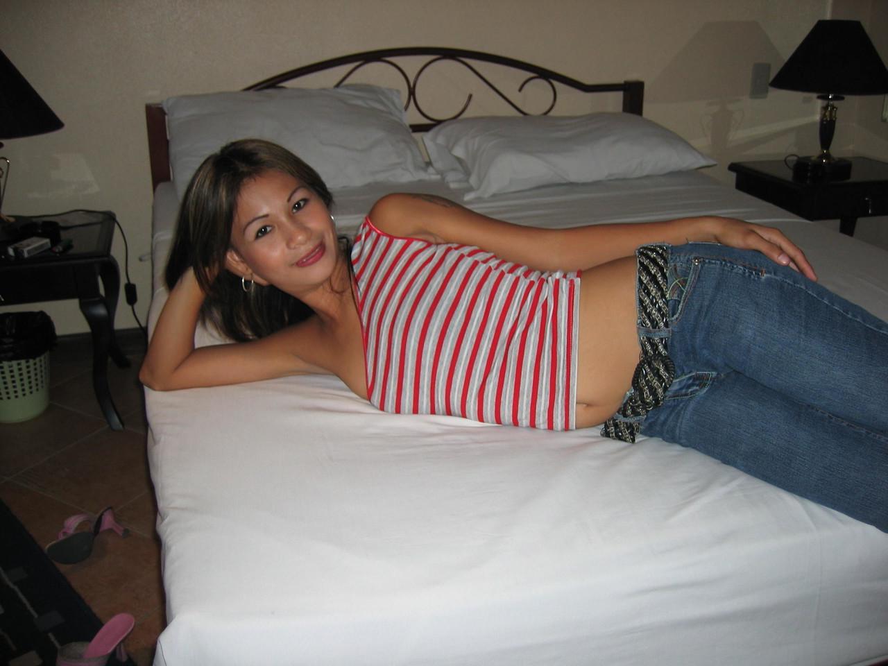 20P Pinay bargirl se quita la camisa para posar con sujetador sin tirantes y jeans en una cama