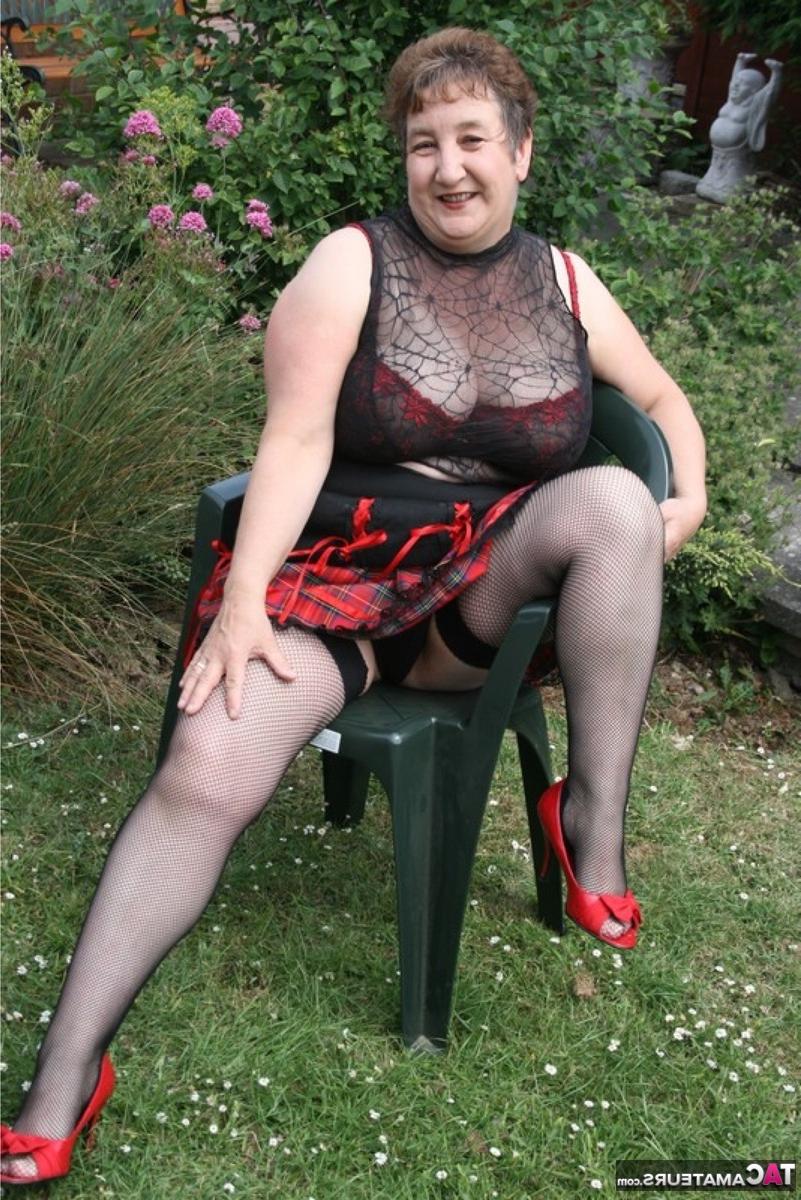 16P Die ältere britische BBW Kinky Carol zeigt ihr Unterrock-Höschen und ihren BH in einem Garten
