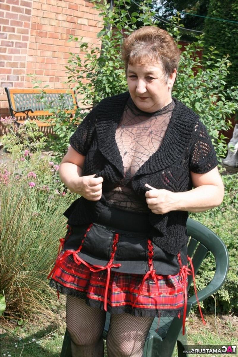 16P Die ältere britische BBW Kinky Carol zeigt ihr Unterrock-Höschen und ihren BH in einem Garten