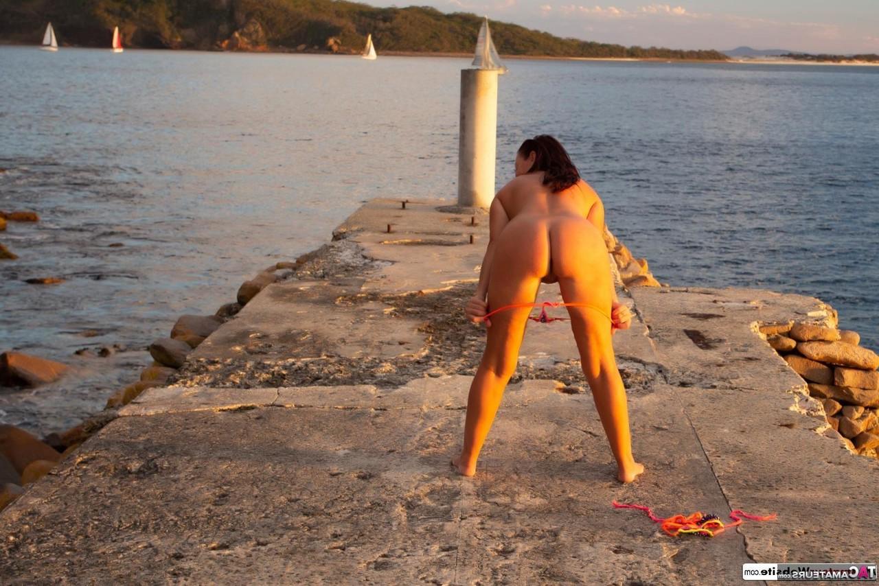 16P Brunette MILF Roxeanne models totally naked on a concrete pier