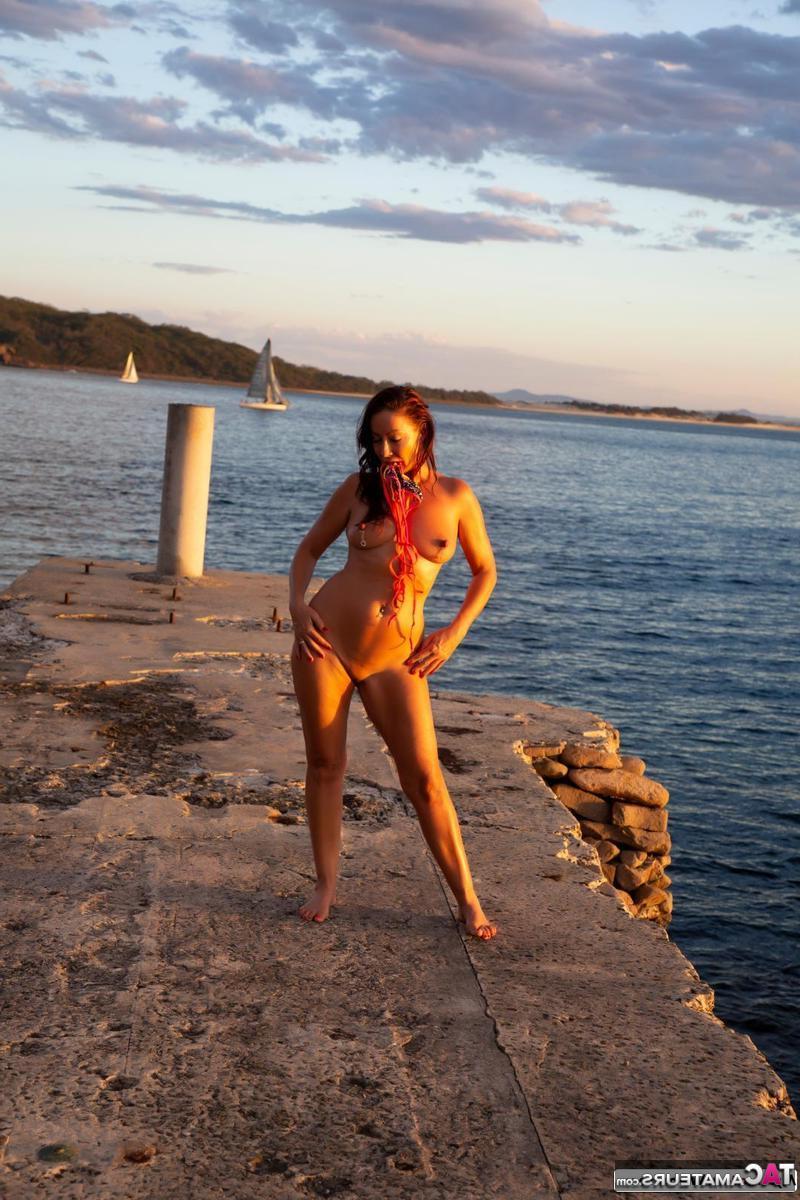 16P Brunette MILF Roxeanne models totally naked on a concrete pier