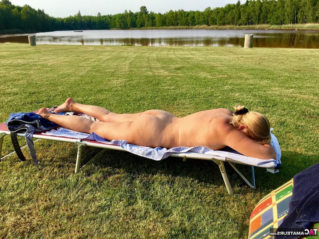 20P Loira amadora com excesso de peso toma banho de sol com óculos escuros à beira do rio