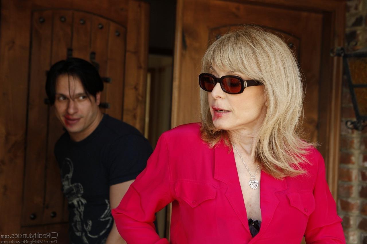 20P Nina Hartley, mature et chaude, suce la grosse bite d'un jeune homme et le chevauche dans la salle de bain.
