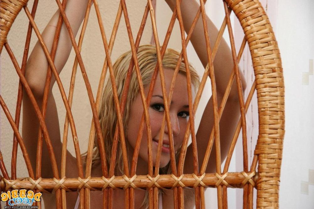 15P Hermosa joven rubia hace topless en una silla de mimbre en ropa interior rosa