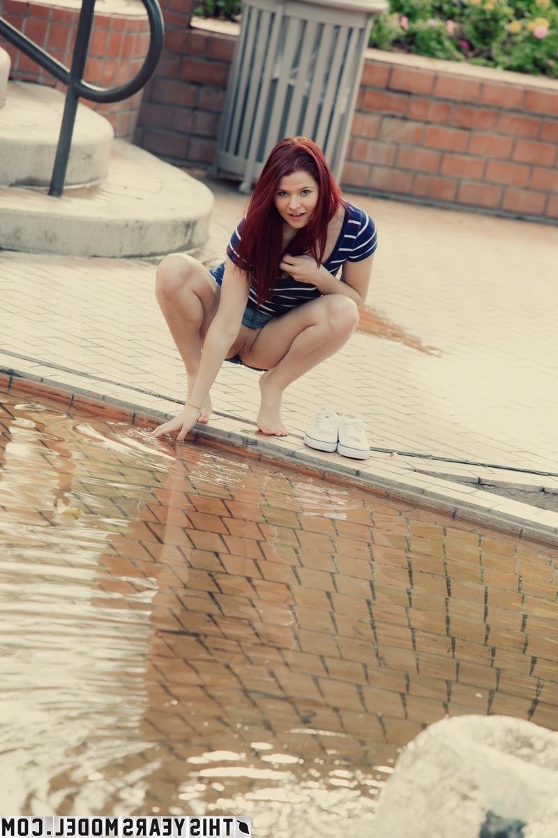 15P Mindy Corin, rousse naturelle, s'expose dans un parc public.