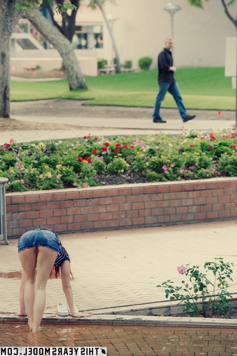 15P Mindy Corin, rousse naturelle, s'expose dans un parc public.