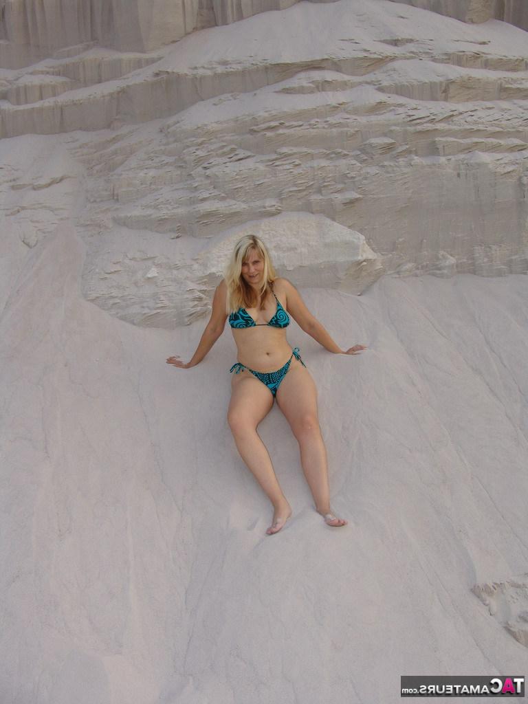 20P La blonde mature Sweet Susi enlève son bikini pour poser nue dans un bac à sable.