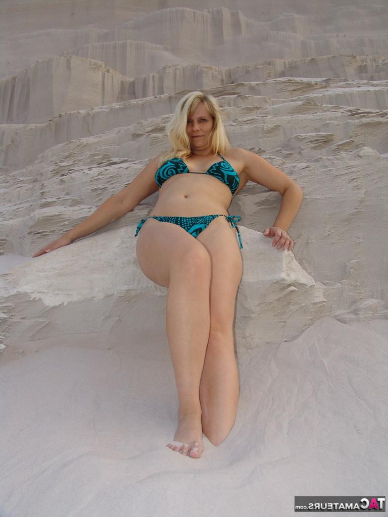 20P La blonde mature Sweet Susi enlève son bikini pour poser nue dans un bac à sable.