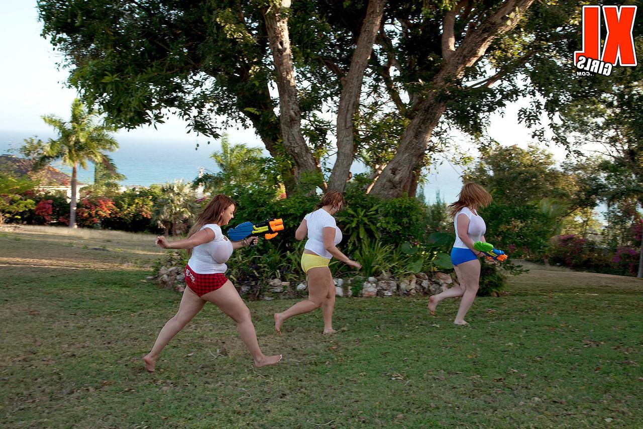 16P Des filles aux gros seins trempent des t-shirts blancs dans une cour avec des pistolets à eau super-soakers.