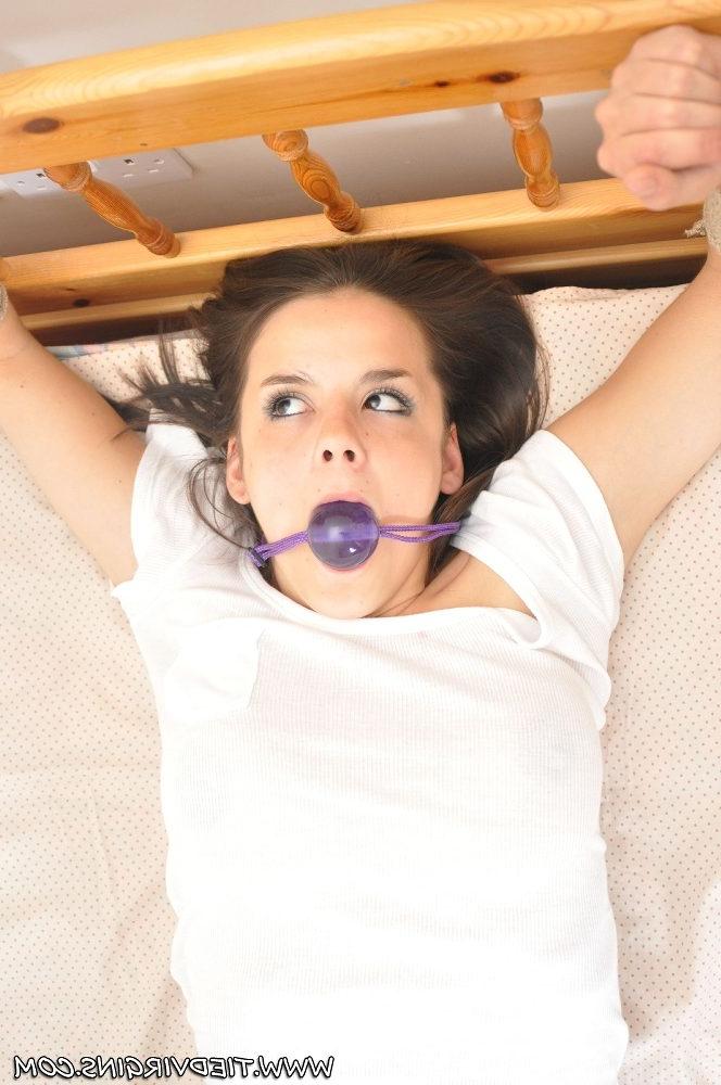 12P Dieses zierliche weiße Mädchen lässt ihre Brüste entblößen, während es mit einem Hodenknebel an ein Bett gefesselt wird