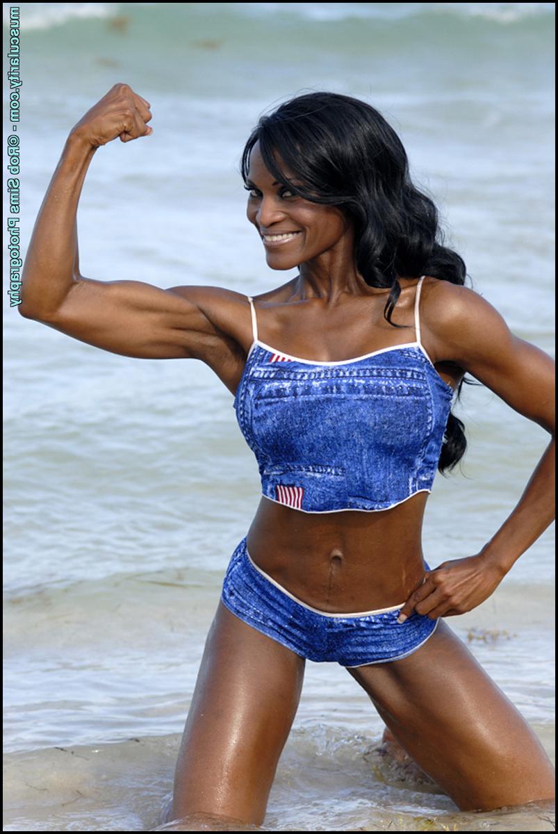 15P La culturista negra Debra Dunn flexiona sus músculos en la playa con un traje vaquero