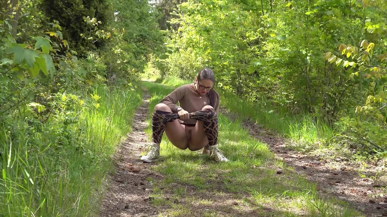 15P Chica blanca con gafas se baja las mallas para orinar en un camino en el bosque