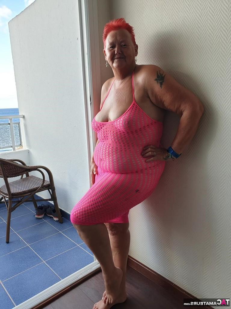 20P Fette Oma mit kurzen roten Haaren spreizt mit dem Finger ihre Muschi auf dem Balkon am Meer