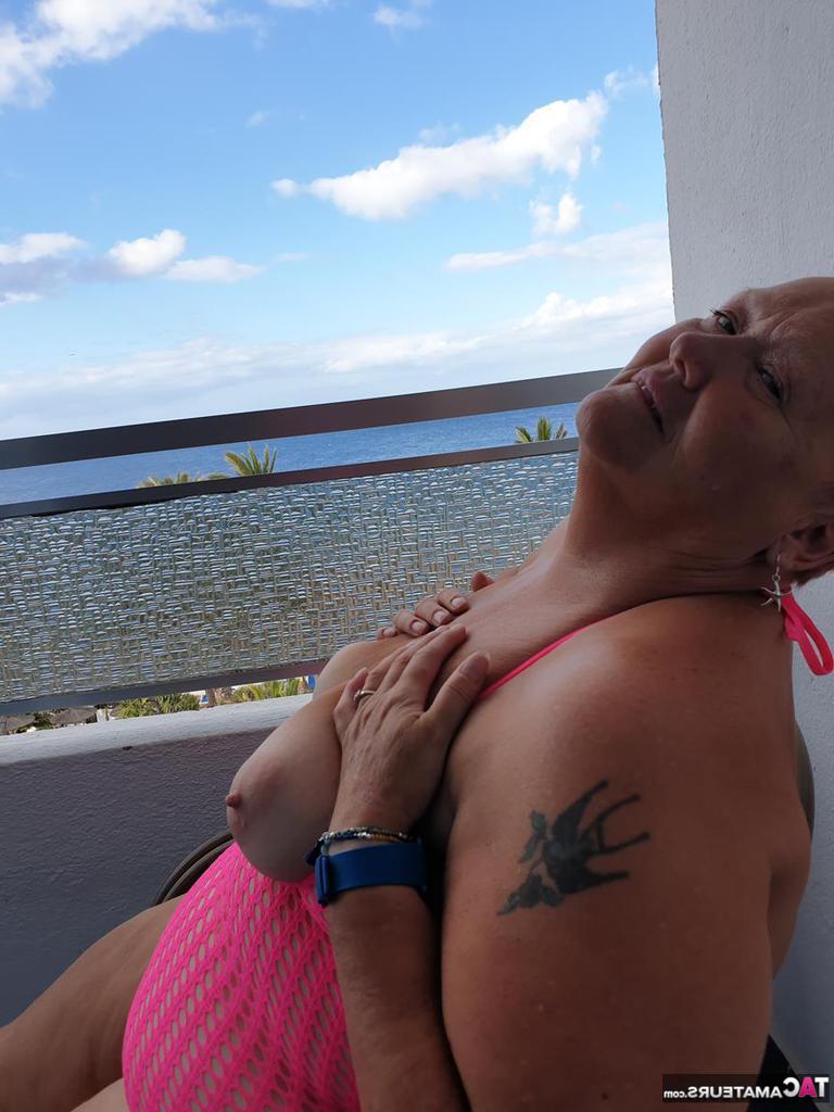 20P Fette Oma mit kurzen roten Haaren spreizt mit dem Finger ihre Muschi auf dem Balkon am Meer