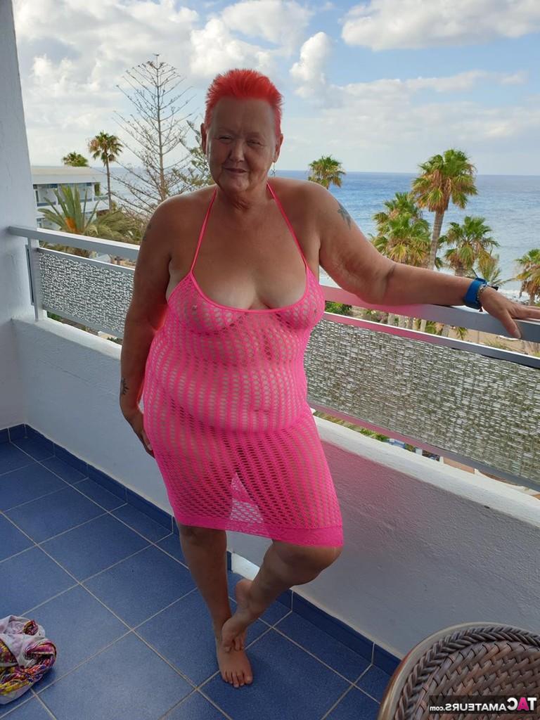 20P Fette Oma mit kurzen roten Haaren spreizt mit dem Finger ihre Muschi auf dem Balkon am Meer