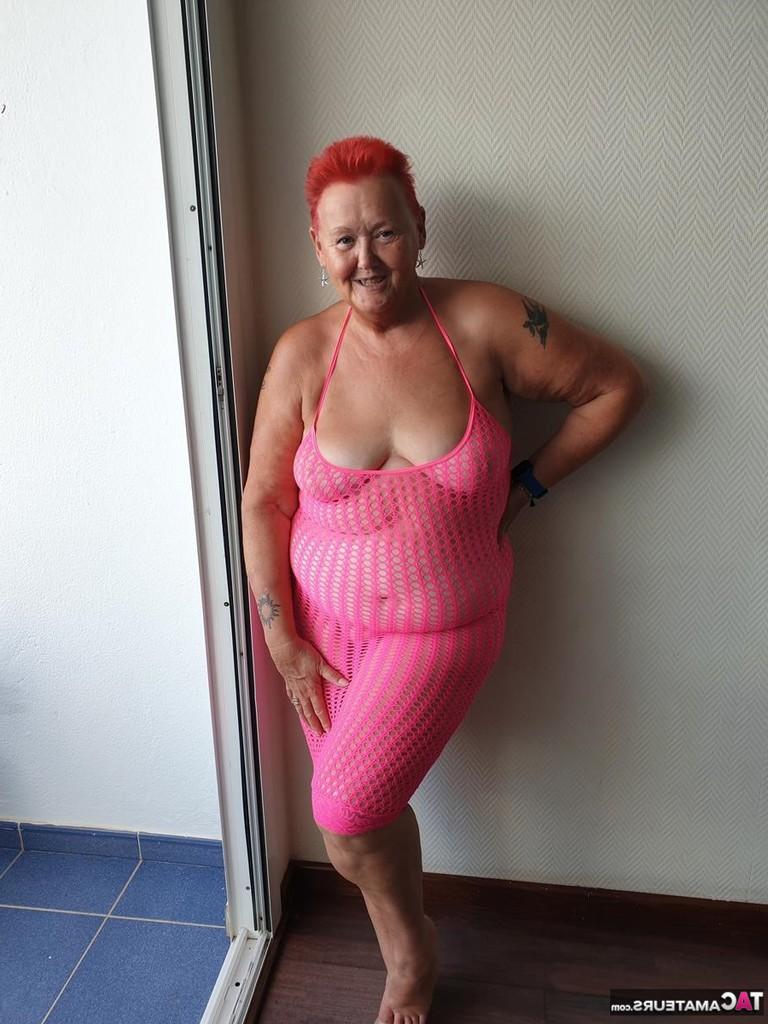 20P Fette Oma mit kurzen roten Haaren spreizt mit dem Finger ihre Muschi auf dem Balkon am Meer