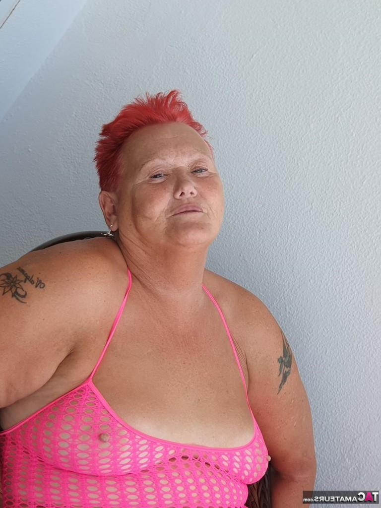 20P Fette Oma mit kurzen roten Haaren spreizt mit dem Finger ihre Muschi auf dem Balkon am Meer
