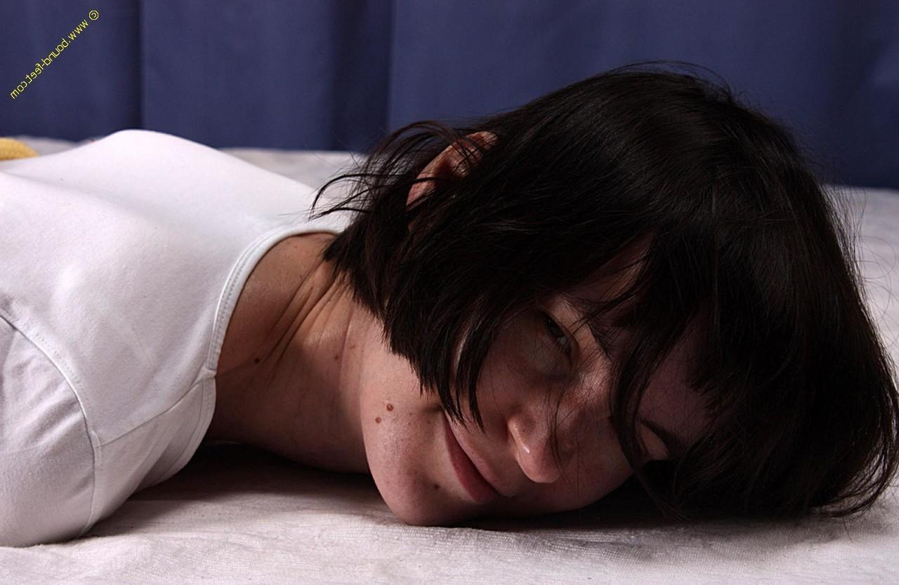 16P Brunette girl is left face down on a bed while hogtied in a T-shirt and undies