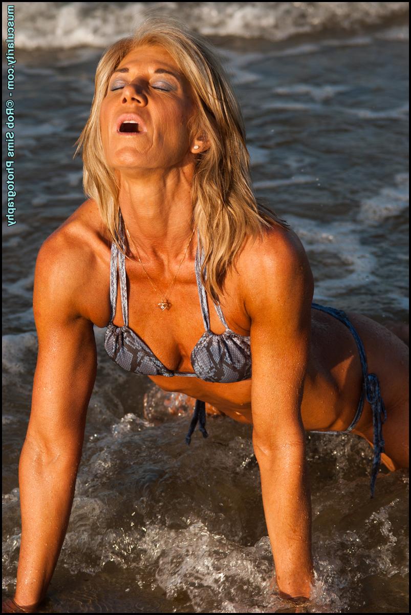 15P Blonde bodybuilder Deb Arbs flexes her muscles on a muddy beach in a bikini