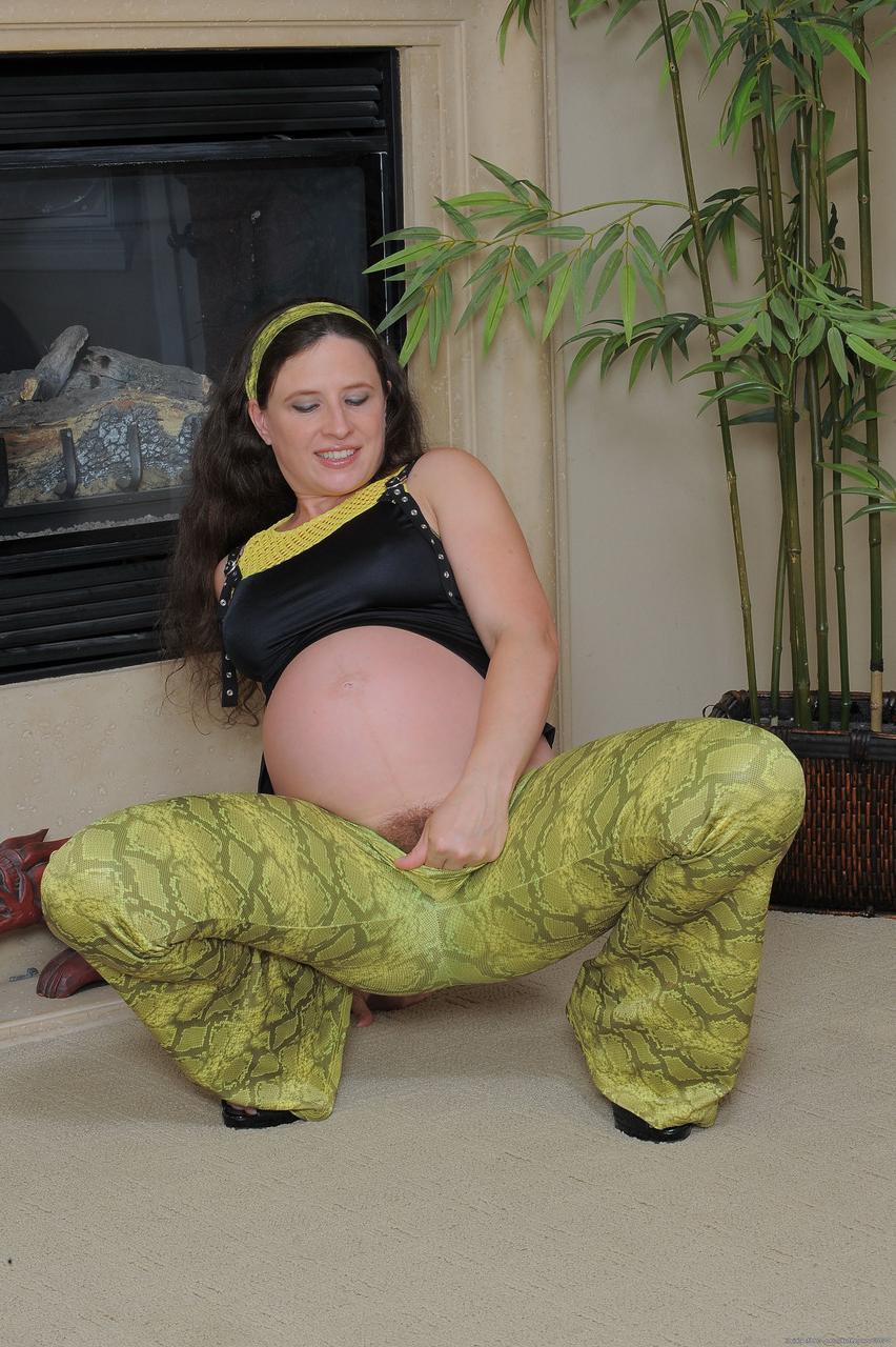 20P Angela, une jeune amateur enceinte, doigte sa chatte poilue et son cul près de la cheminée.