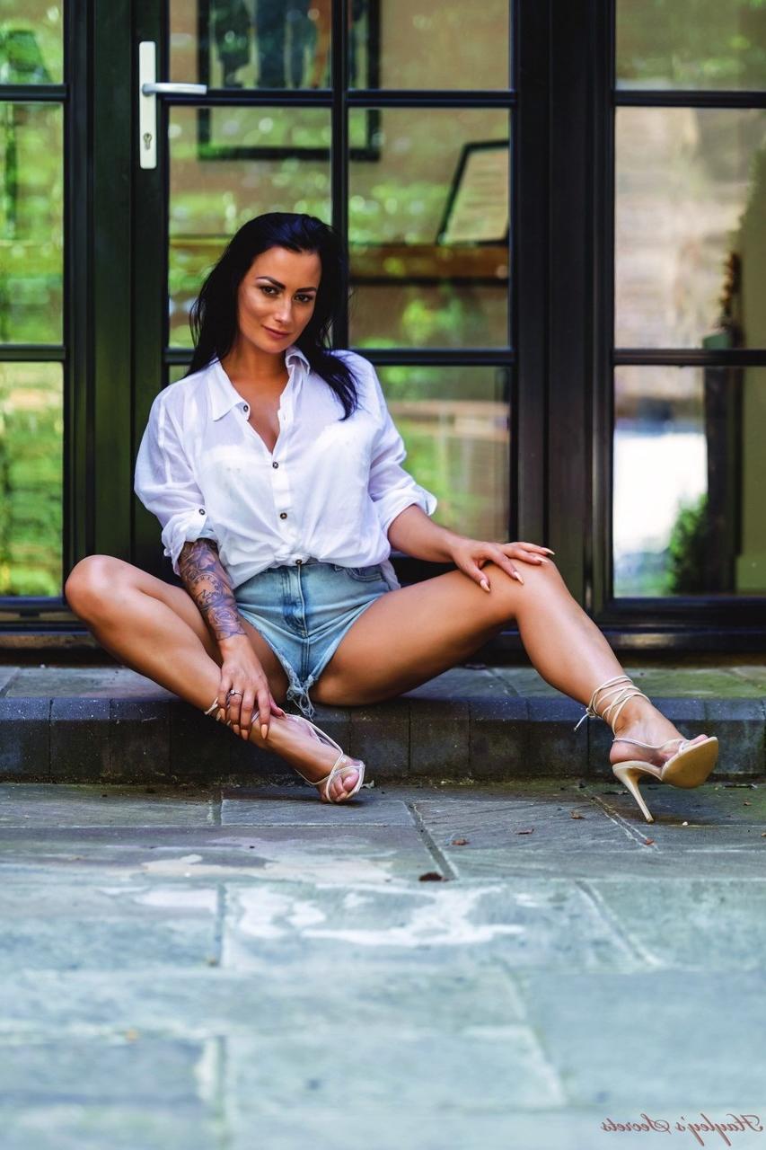 12P Das tätowierte britische Model Kelli Smith entblößt ihren tollen Körper in High Heels vor einer Terrassentür