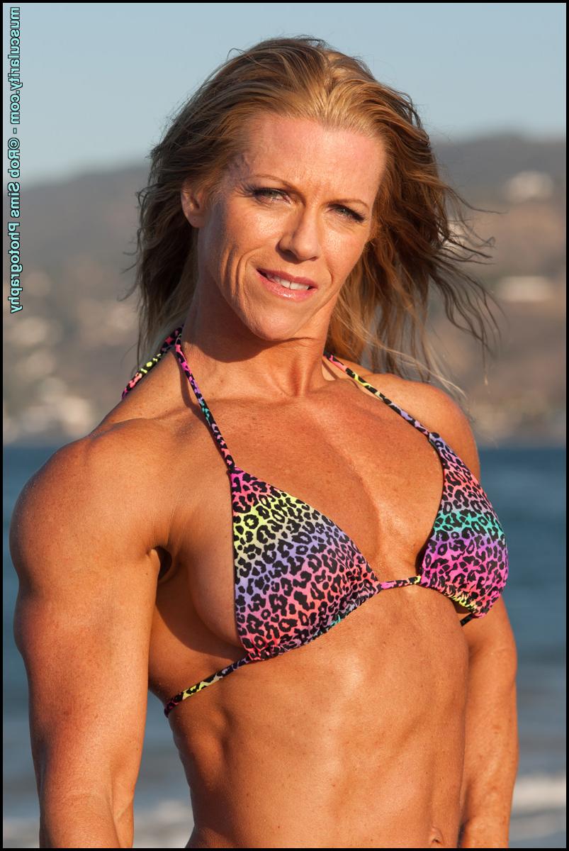 15P Bodybuilder Amy Bowen flexes her muscles on a beach in a bikini