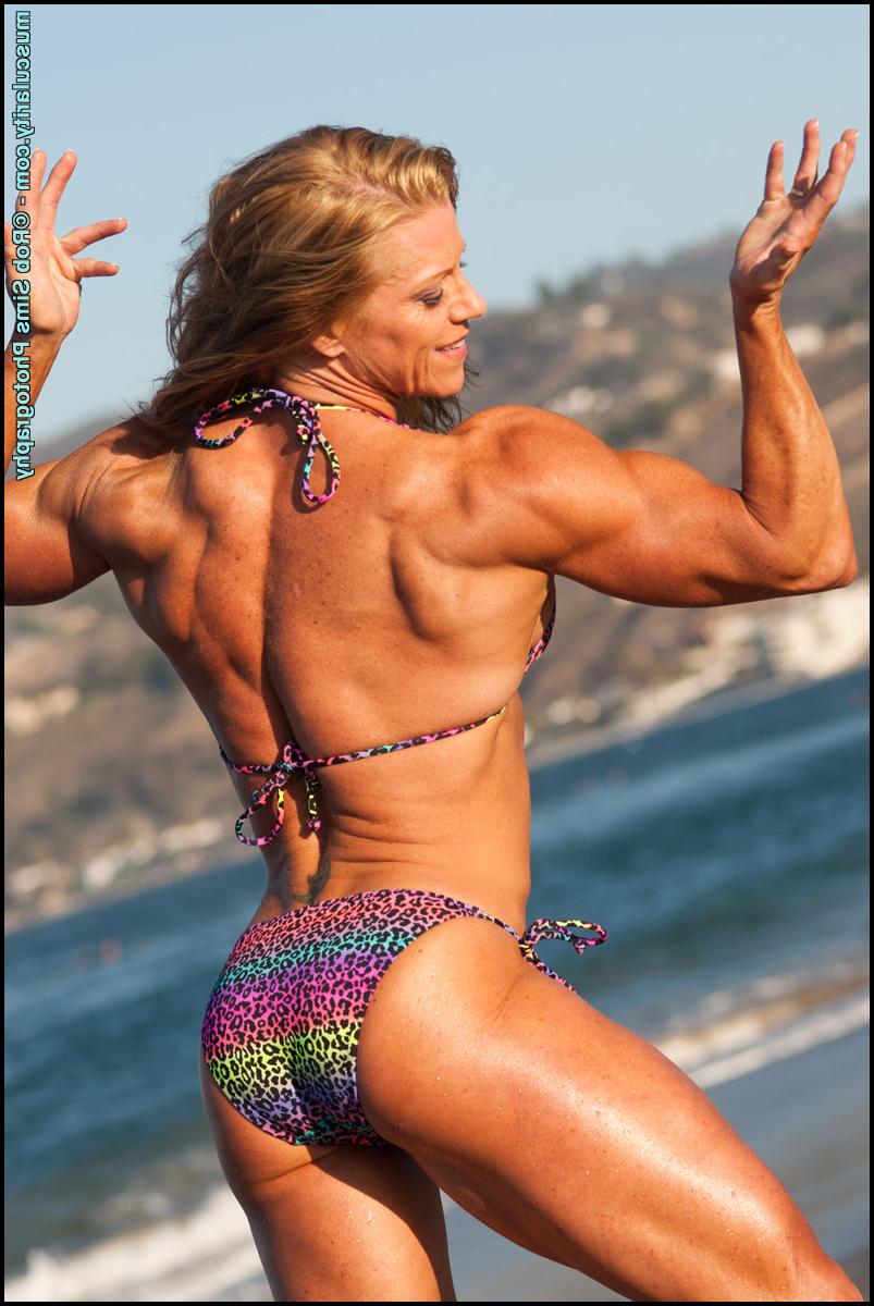 15P Bodybuilder Amy Bowen flexes her muscles on a beach in a bikini