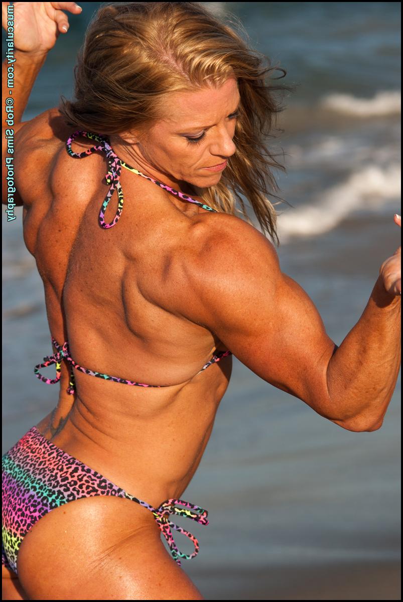 15P Bodybuilder Amy Bowen flexes her muscles on a beach in a bikini