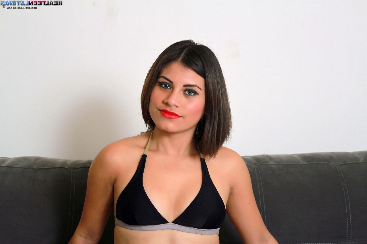 15P Gretel, jeune latina, arbore des lèvres rouges tout en portant un bikini avec des talons.