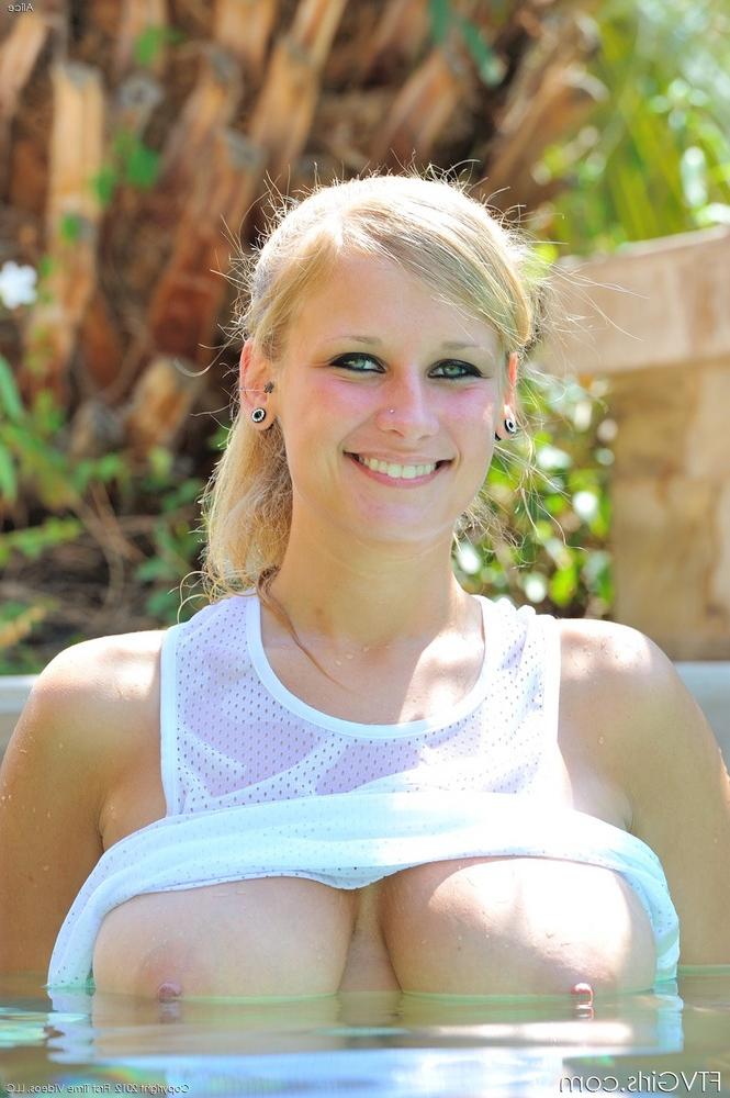 16P Rubia caliente y afeitada tomando el sol con su coño abierto junto a la piscina dejando colgar sus tetas desnudas