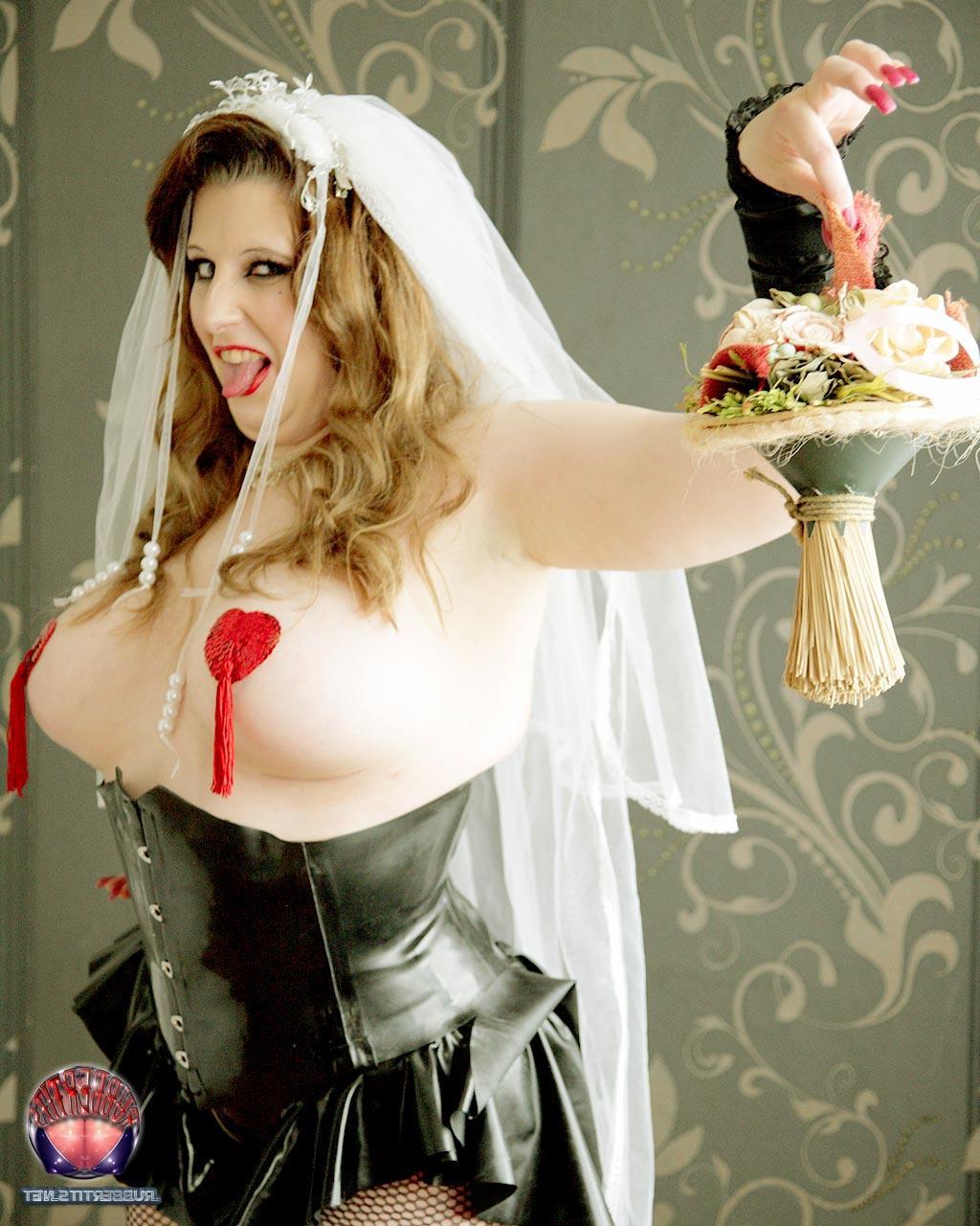 16P Une mariée rousse arbore des cache-tétons dans un corset en latex noir.