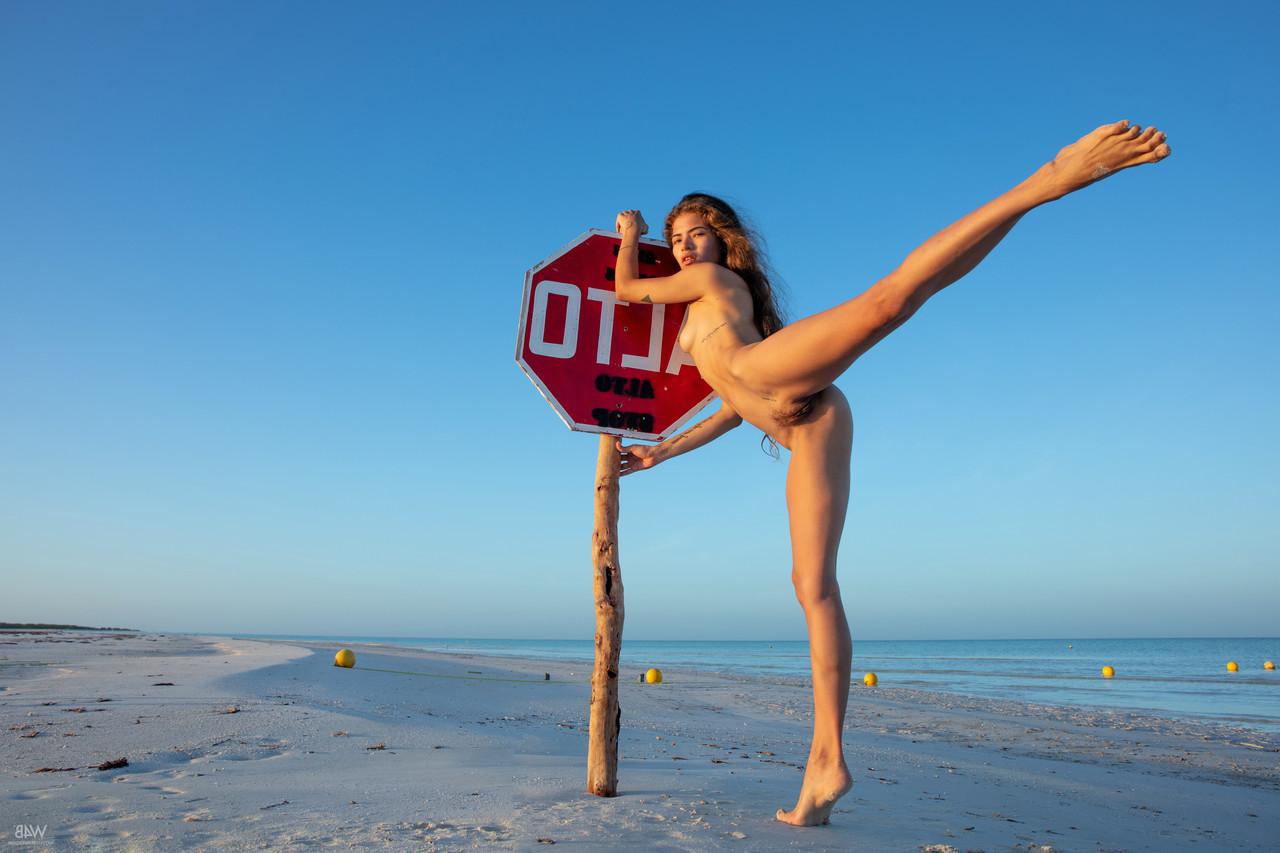 20P Slender Latina Irene Rouse shows her flexibility while posing naked on a beach