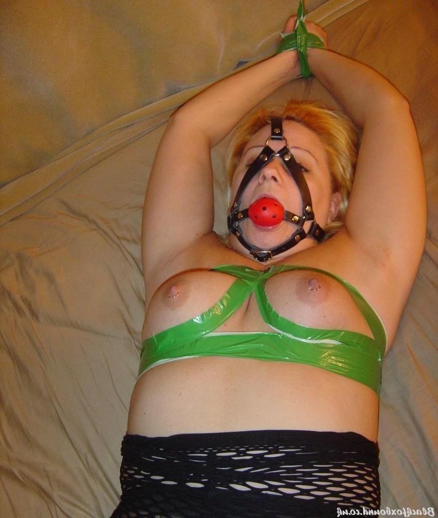16P Une blonde potelée arbore un bâillon-boule alors qu'elle est attachée en collants.