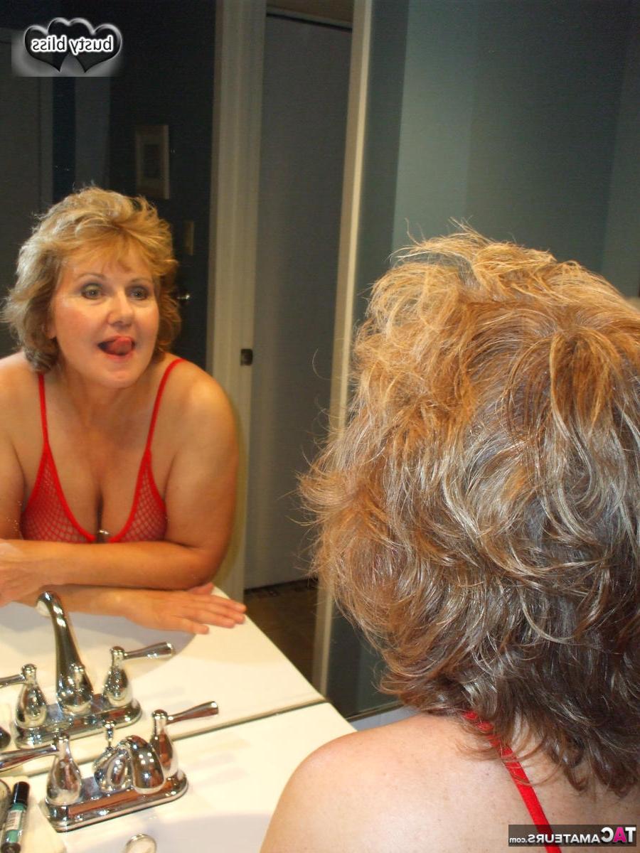 16P Busty Bliss, femme mûre, joue avec un gode tout en portant un maillot de bain transparent.