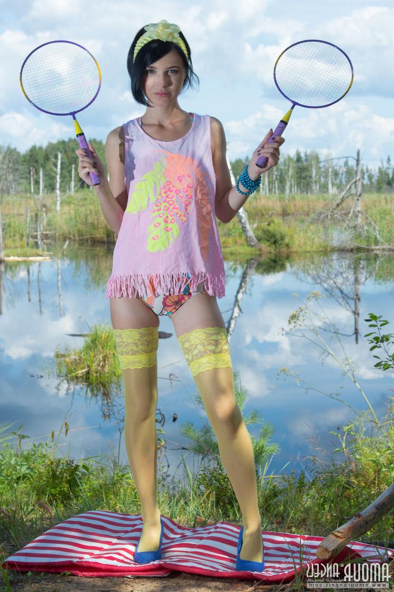 20P Menina adolescente de cabelos escuros coloca suas raquetes de badminton e fica nua