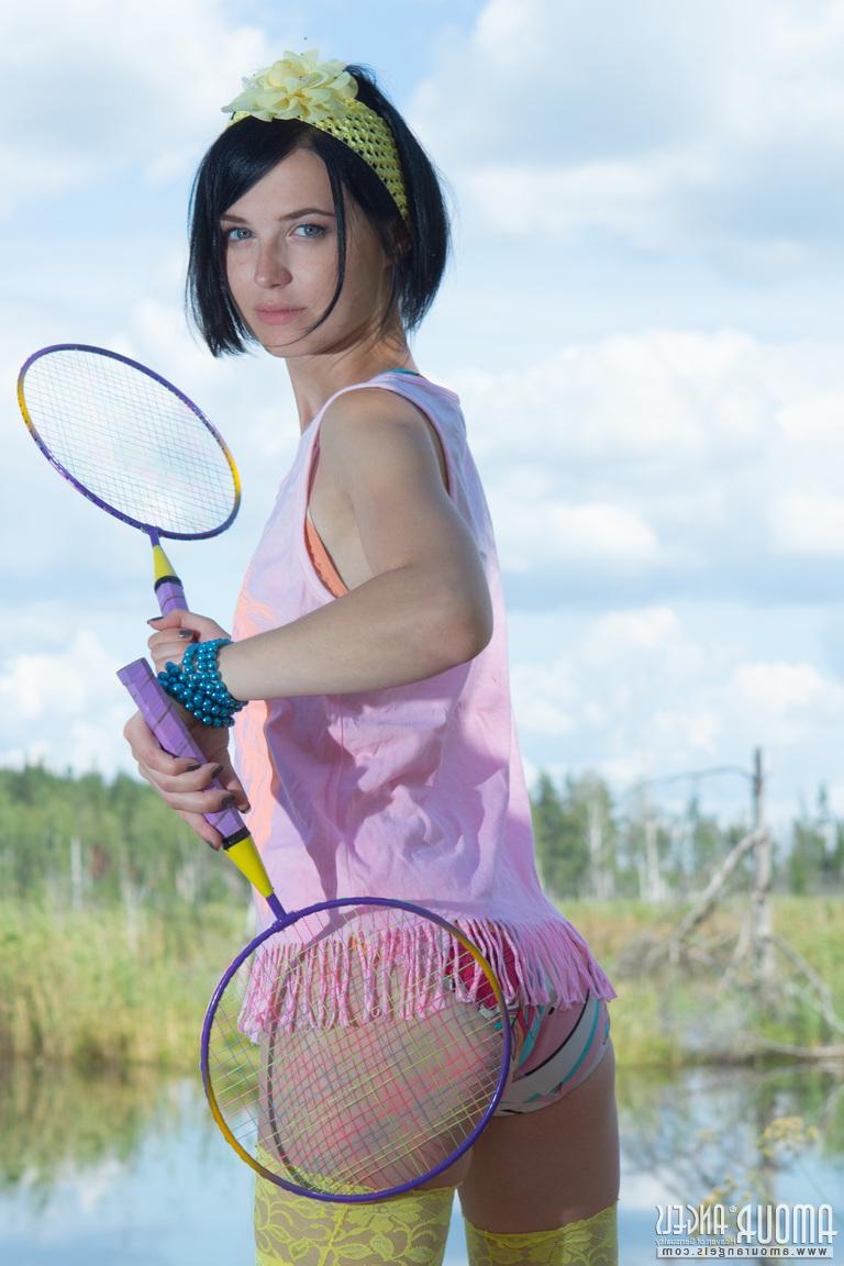 20P Menina adolescente de cabelos escuros coloca suas raquetes de badminton e fica nua