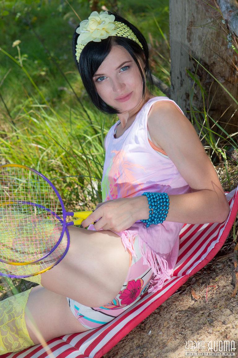 20P Menina adolescente de cabelos escuros coloca suas raquetes de badminton e fica nua