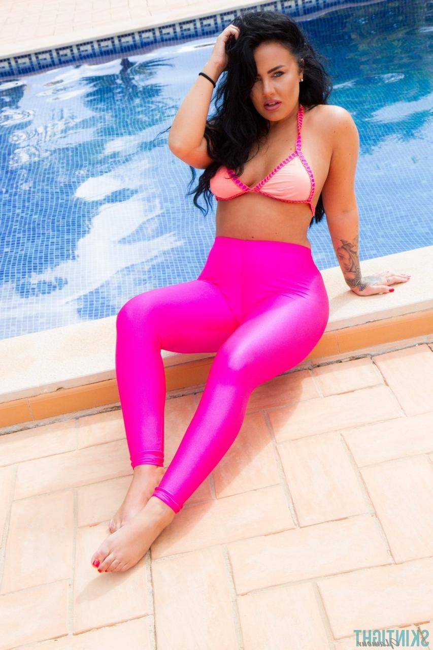 12P A modelo glamourosa Olivia Paige coloca leggings rosa sobre a parte de baixo do biquíni à beira da piscina