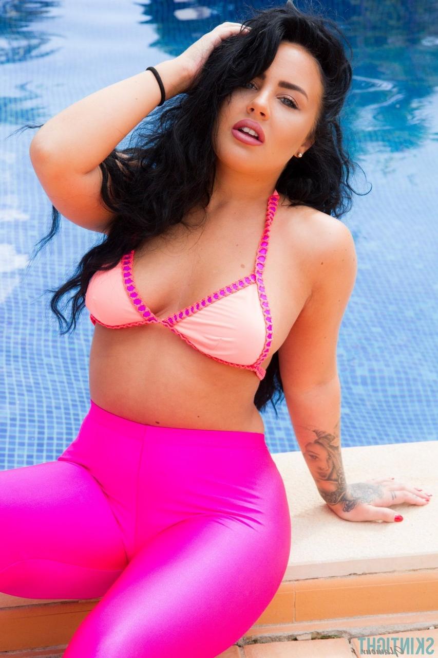 12P A modelo glamourosa Olivia Paige coloca leggings rosa sobre a parte de baixo do biquíni à beira da piscina