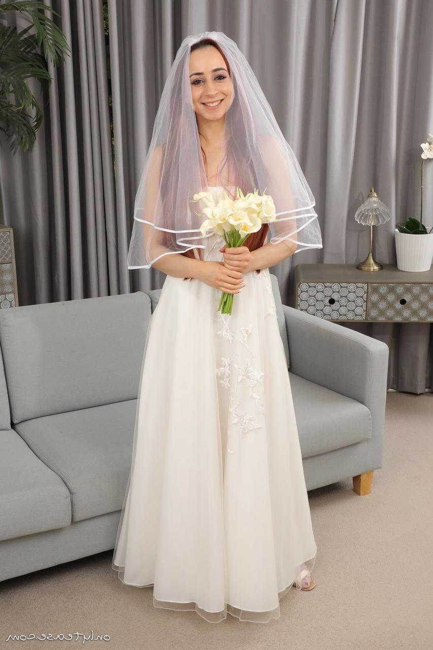 16P La mariée rousse Tania Aresti se met nue avec un voile, des jarretières et des bas de nylon.