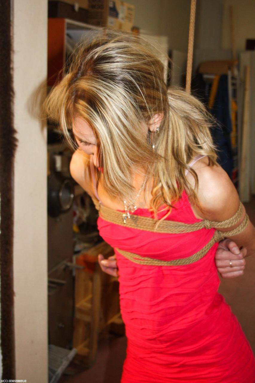 20P Irena, une jeune femme vêtue d'une robe et de talons sexy, a du mal à se libérer du bondage par corde.