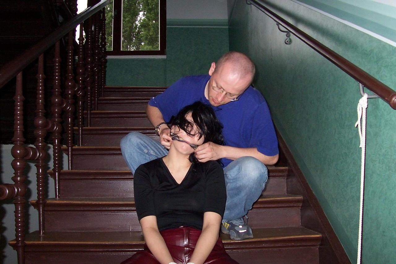 16P Brunette chick finds herself gagged and bound in leather pants on the stairs