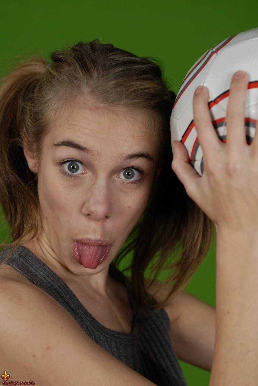 16P Das zierliche Mädchen Kelly entblößt ihre Brust, während sie einen Fußball hält