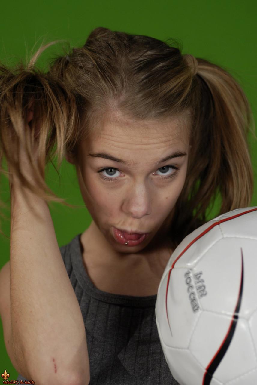 16P Das zierliche Mädchen Kelly entblößt ihre Brust, während sie einen Fußball hält