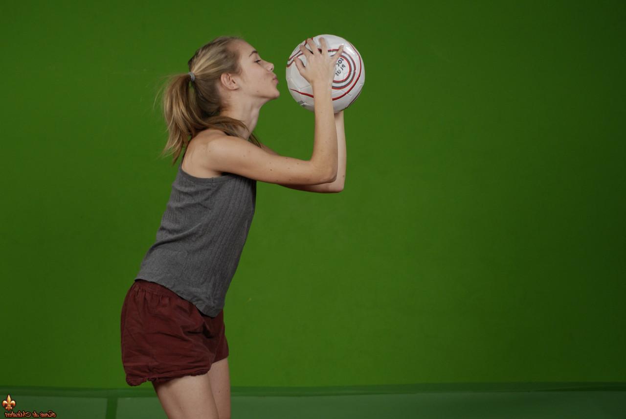 16P Das zierliche Mädchen Kelly entblößt ihre Brust, während sie einen Fußball hält